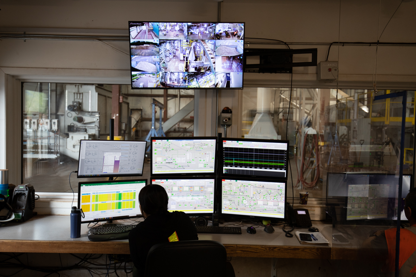 person on front of 6 computer screens in a pellet mill.