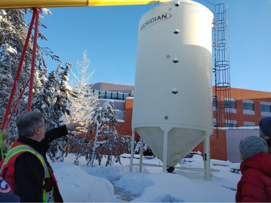 People outside a biomass facility in Yellowknife in the snow.