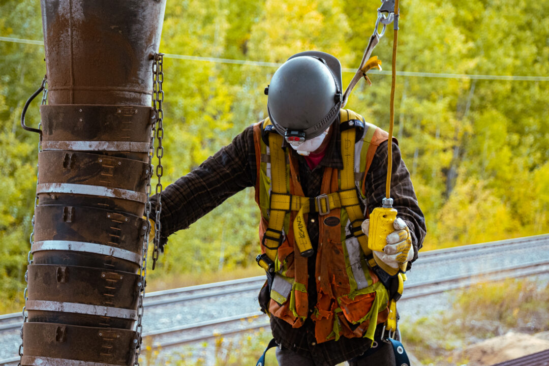 Person in safety gear pouring wood pellets into a railcar